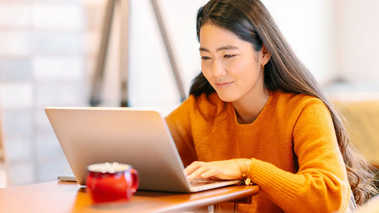 A smiling woman using a laptop.
