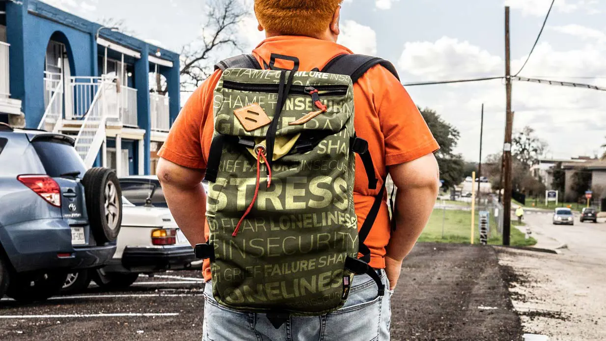 Student wearing backpack waiting for bus.