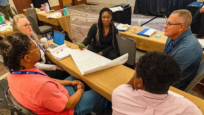 A group of people talking at a table during CPI training.