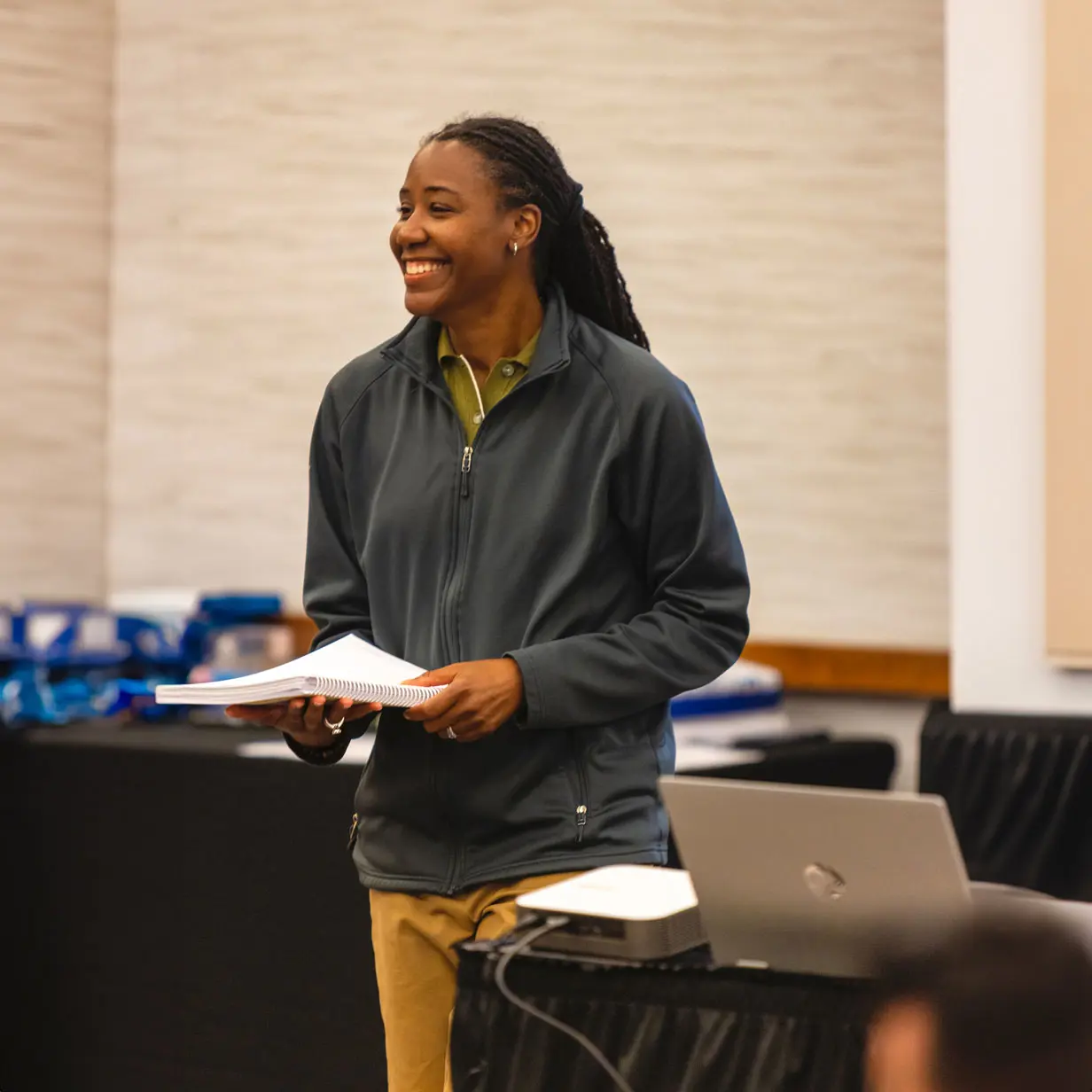 A smiling woman holding a notebook.